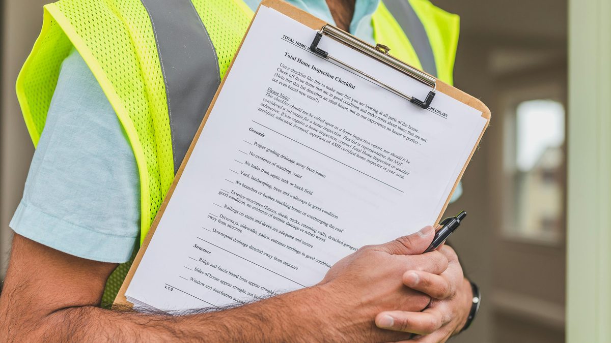 An inspector holding a clipboard checklist — compliance and auditability as a design input