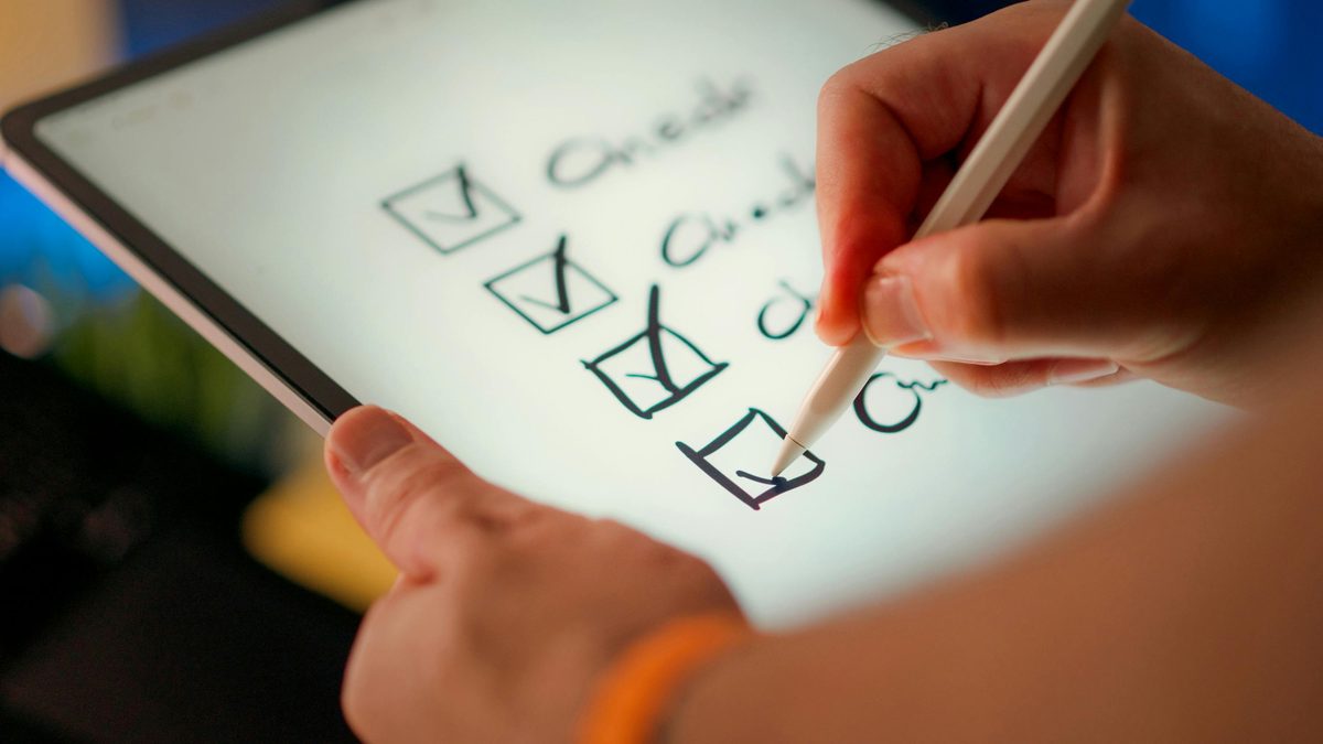 A hand ticking boxes on a checklist tablet — assessing readiness across each dimension