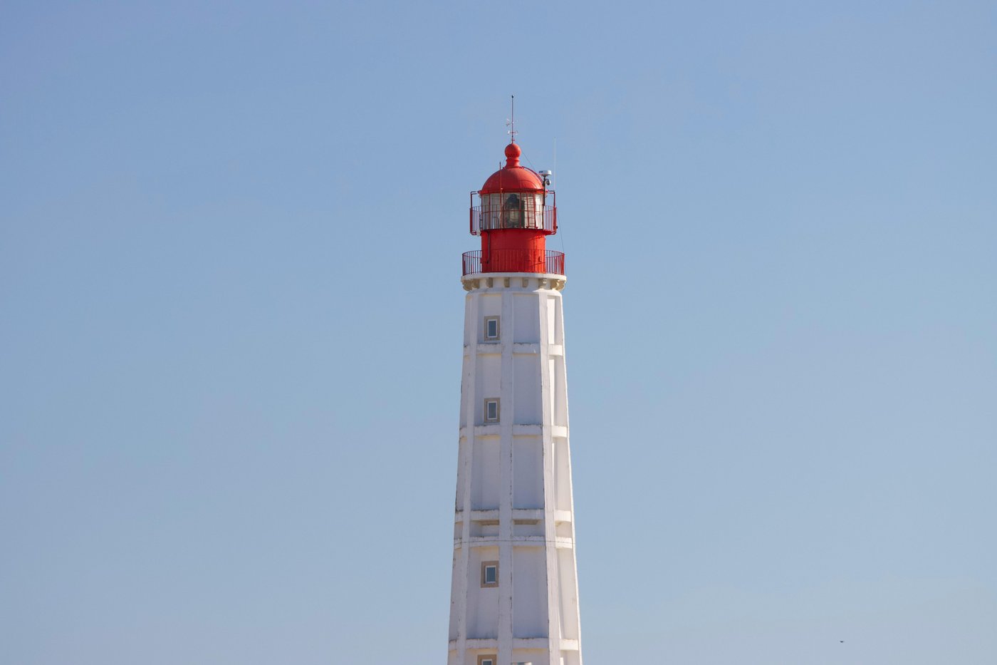 A red-and-white lighthouse against a clear sky — steady, watchful operation